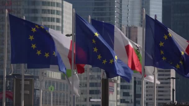 Avrupa Birliği bayrakları ve Fransız bayrakları Paris 'teki gökdelenlerin arka planına karşı rüzgarda dalgalanıyor. Yüksek kalite 4k görüntü - Video, Çekim