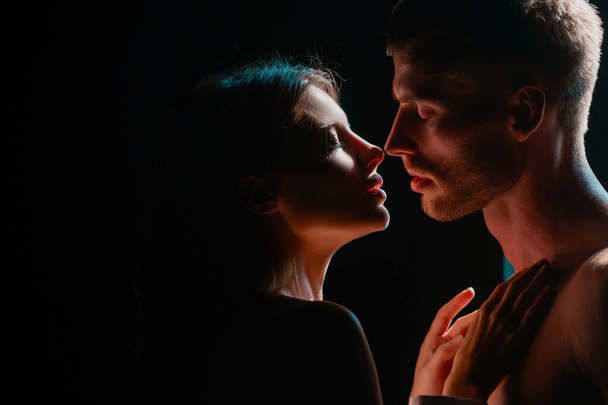 Beautiful loving couple posing on dark backgroung with night lights. Close up face of a beautiful young couple in love embracing, romance and and affection - Foto, immagini