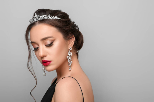 Beautiful young woman wearing luxurious tiara on light grey background, space for text - Foto, Imagen