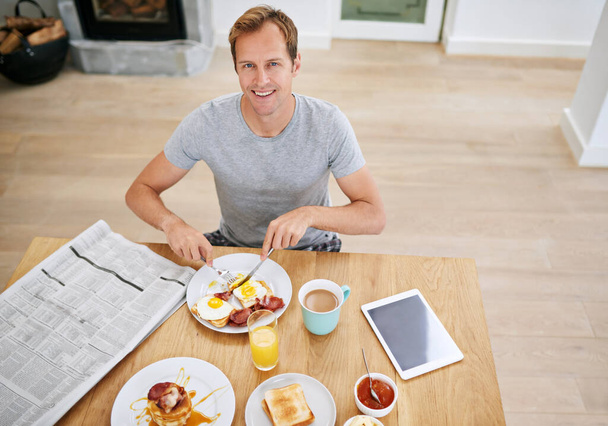 1日を始めるのに最適な方法です。家で朝食を食べるハンサムな男の高い角度の肖像画 - 写真・画像