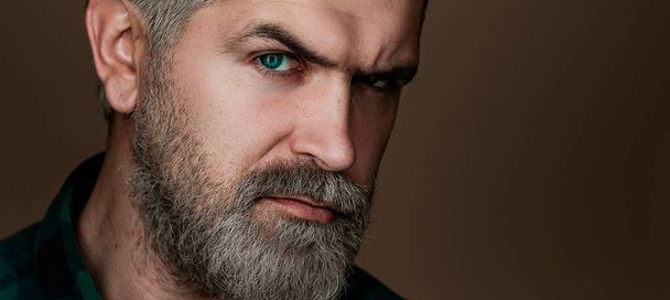 Professional model and professional photo shoot. Head and shoulders portrait of a bearded middle-aged man looking at the camera over a grey studio background with copy space - Фото, изображение