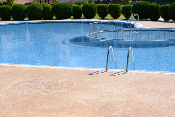 Clean swimming pool with metal ladder on sunny day outdoors - Photo, Image