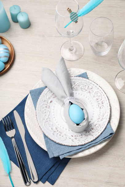 Festive table setting with bunny ears made of light blue egg and napkin, above view. Easter celebration - Foto, afbeelding