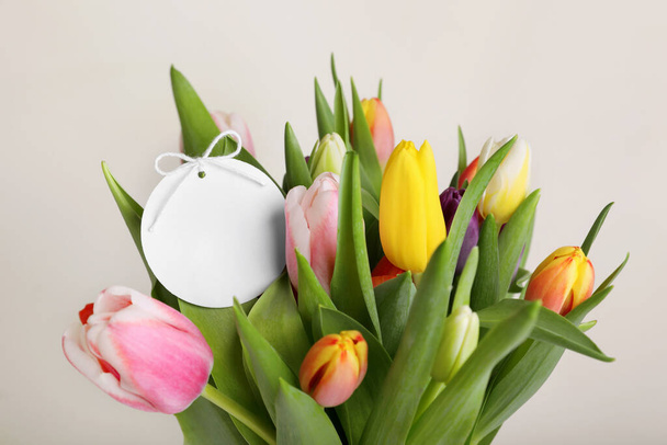 Bouquet of colorful tulips with blank card on white background, closeup - Fotó, kép