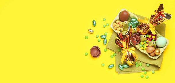 Chocolate Easter eggs and candies on yellow background with space for text - Foto, Imagem