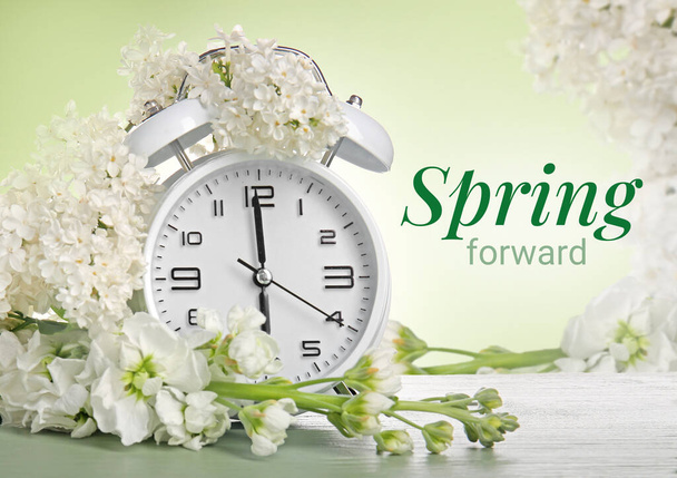 Alarm hodiny a bílé květy na zeleném pozadí. Jarní čas - Fotografie, Obrázek