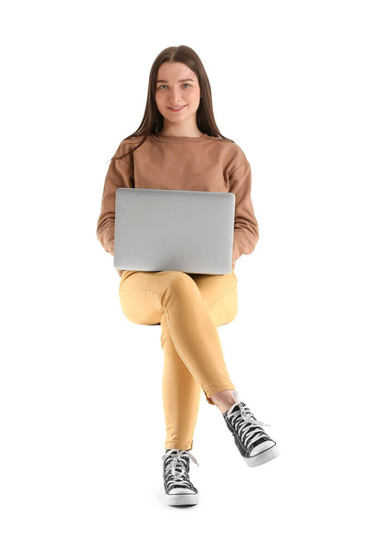 Jolie jeune femme avec ordinateur portable assis sur une chaise sur fond blanc - Photo, image
