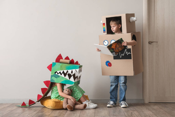 Malé děti v kartónových kostýmech si hrají u světlé stěny - Fotografie, Obrázek