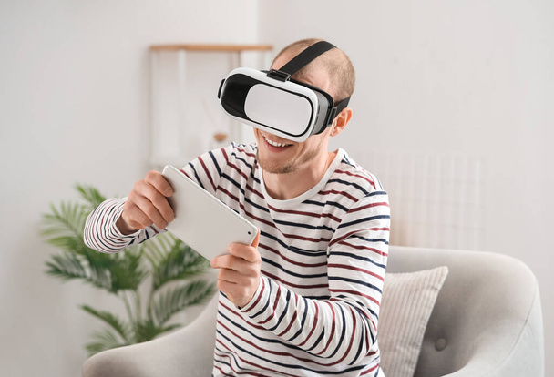Молодий чоловік з VR окулярами та планшетним комп'ютером вдома
 - Фото, зображення