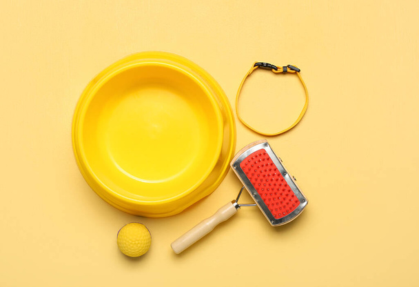 Empty bowl for pet food, ball, grooming brush and collar on color background - Foto, immagini