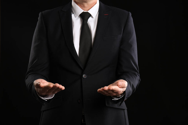Ώριμος σύμβουλος επιχειρήσεων δείχνει τα χέρια σε σκούρο φόντο, closeup - Φωτογραφία, εικόνα