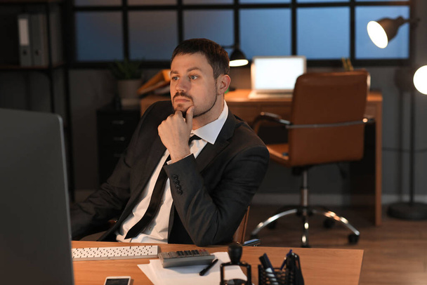 Thoughtful male accountant working in office at night - Photo, Image