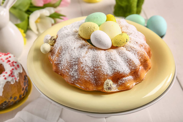 Stojak na deser ze smacznym ciastem wielkanocnym i jajkami na jasnodrewnianym stole, zbliżenie - Zdjęcie, obraz