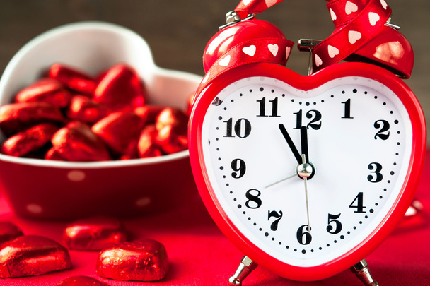 Amore orologio rosso a forma di cuore e cioccolatini dolci. Tempo per l'amore
.  - Foto, immagini