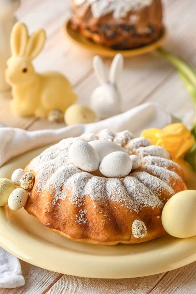 Assiette avec gâteau de Pâques savoureux et oeufs peints sur table en bois blanc - Photo, image
