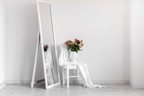 Váza gyönyörű alstroemeria virágok a széken és a tükör közelében fény fal - Fotó, kép