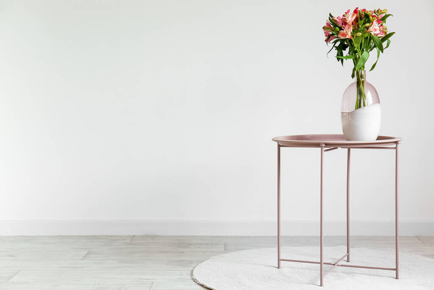 Işık duvarının yanındaki masada vazo ve alstromerya çiçekleri. - Fotoğraf, Görsel