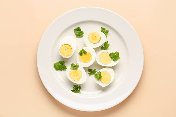 Plate with halves of delicious boiled eggs and parsley on beige background - Photo, Image