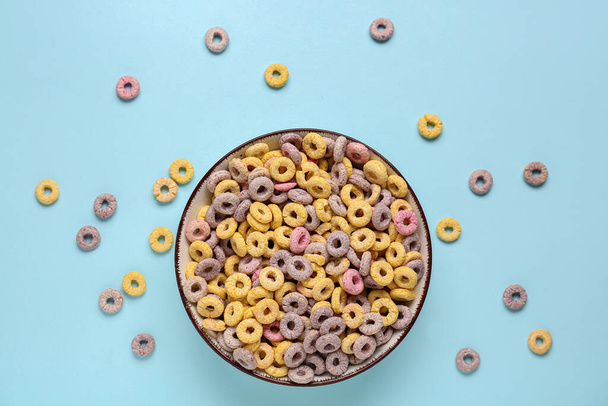 Bowl of colorful cereal rings on blue background - Фото, зображення