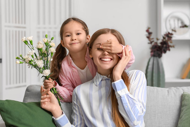 Bambina con fiori che chiudono gli occhi di sua madre a casa - Foto, immagini