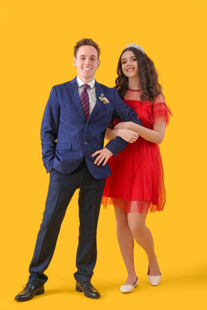 Beautiful couple dressed for prom on yellow background - Фото, изображение