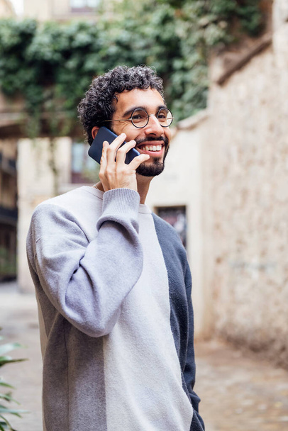 young man with beard and glasses smiling happy talking on the phone, concept of lifestyle and technology of communication - Photo, Image