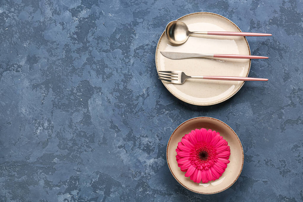 Накрытие стола с красивым цветком герберы на синем фоне гранжа - Фото, изображение