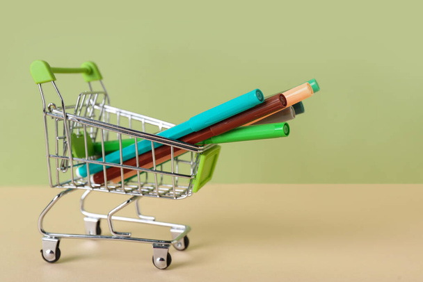 Shopping cart with felt-tip pens on color background - Photo, Image