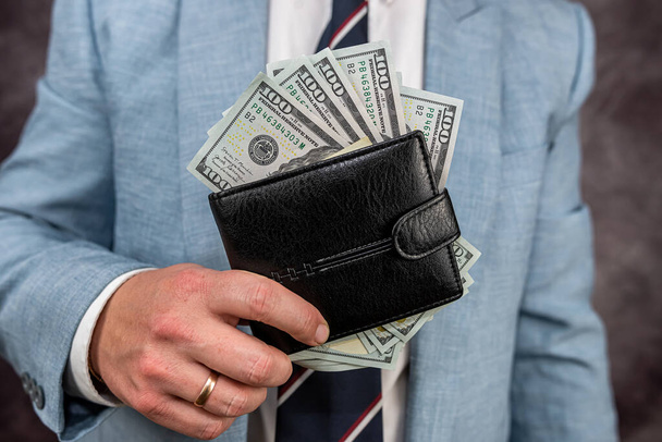 Uomo d'affari in possesso di denaro in portafoglio. Concetto di tangente o salario - Foto, immagini