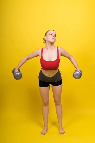 Mosolygó fiatal kövér fitness sportos csábító nő gyakorló egy súlyzóval - Fotó, kép