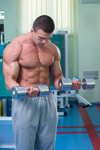 Muscular man working out with dumbbells - Foto, imagen