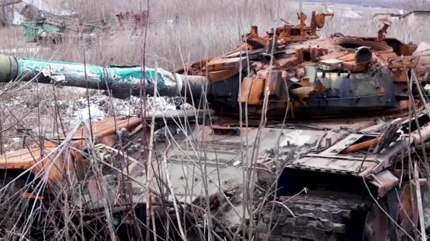 Un tanque oxidado noqueado se encuentra entre la hierba seca en un campo cerca del pueblo. Russian-Ukrainian War 2022-2023 (en inglés). La ofensiva del ejército ruso, la ocupación de territorios ucranianos - Metraje, vídeo