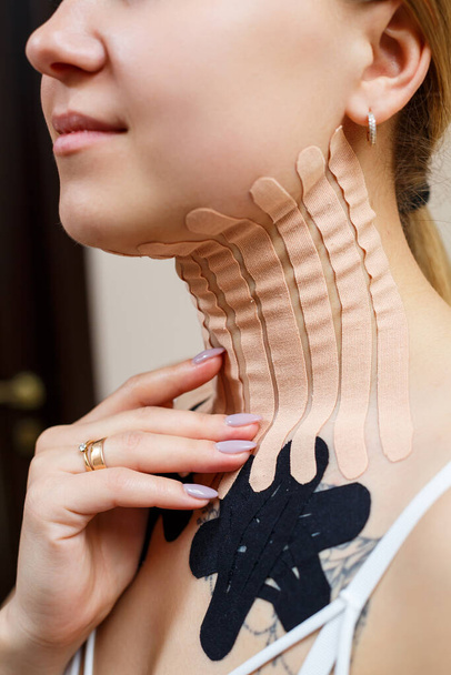 Közelkép egy fiatal nő nyakán lévő szalagról. Kinezioterápia terápiás szalaggal - Fotó, kép