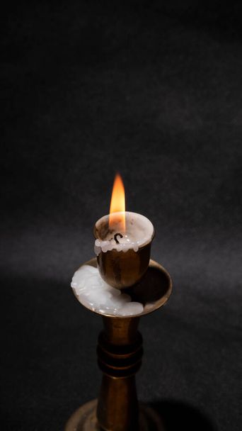 Антикварный бронзовый подсвечник со свечой на столе на черном фоне - Фото, изображение