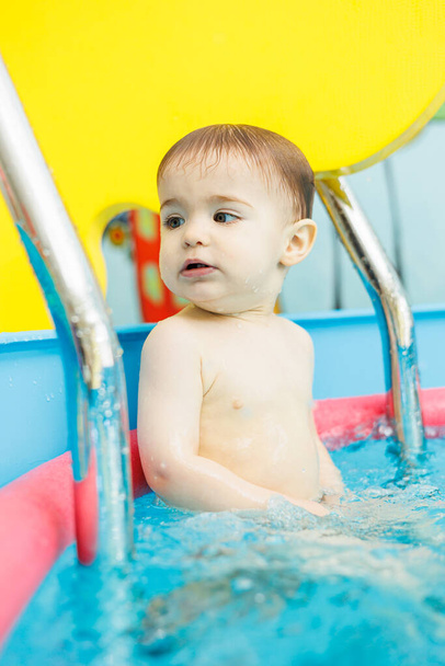 Маленький мальчик 2 года в бассейне. Уроки плавания для маленьких детей. - Фото, изображение