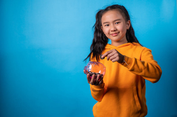 the studio isolated image of the girl holding the piggy bank and saving money - 写真・画像