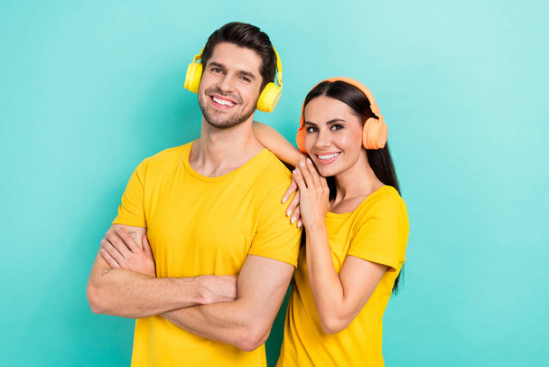Foto creativa de dos personas que usan una camiseta amarilla brazos cruzados confiados usan una camiseta amarilla auriculares inalámbricos aislados en el fondo de color amarillo. - Foto, imagen