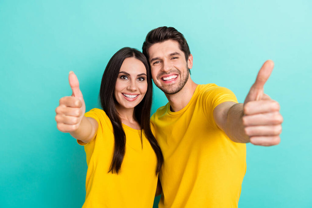 Photo of charming positive husband wife dressed yellow t-shirts cuddling showing you thumbs up isolated turquoise color background. - Foto, imagen
