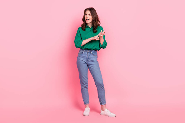 Portrait of satisfied lovely nice girl curly hairstyle green shirt arms on billboard look at offer empty space isolated on pink background. - Fotoğraf, Görsel
