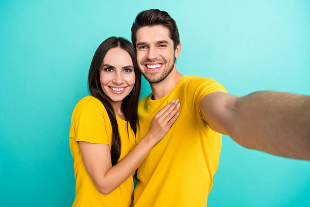 Photo of shiny charming husband wife dressed yellow t-shirts hugging smiling tacking selfie isolated turquoise color background. - Fotografie, Obrázek