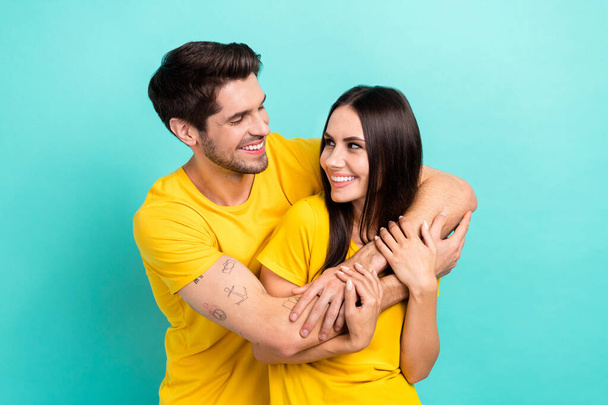 Photo of funny pretty husband wife dressed yellow t-shirts hugging having fun empty space isolated turquoise color background. - Φωτογραφία, εικόνα