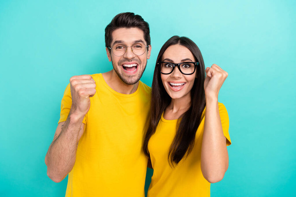 Photo of two people youngsters lovely geeks wear yellow t-shirt fists up celebrate ending graduation hooray isolated on aquamarine color background. - Φωτογραφία, εικόνα