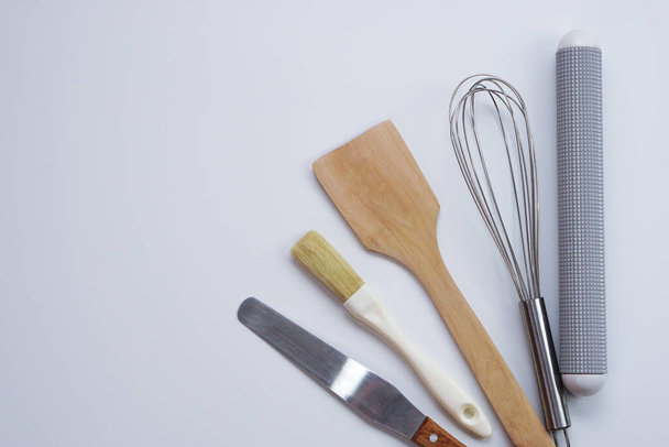 Top view kitchenware wooden rolling pin, wooden spatula and egg beater on white background. Materials or kitchen equipment for bakery. - 写真・画像