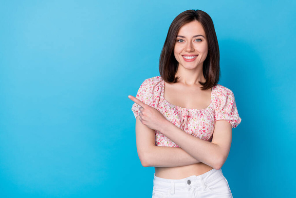 Photo portrait of lovely young lady shining smile point empty space dressed trendy flower print garment isolated on blue color background. - 写真・画像