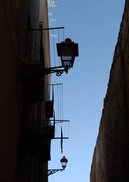 Old buildings with lamps on a narrow street in Italy. - Фото, изображение