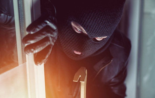 Ladrón entrando en una ventana de la casa con una palanca - Foto, imagen