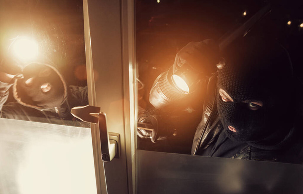Two Burglar breaking in a window of a house at night - Foto, afbeelding