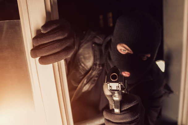 Terrorist of een dief die een pistool op een huis richt - Foto, afbeelding