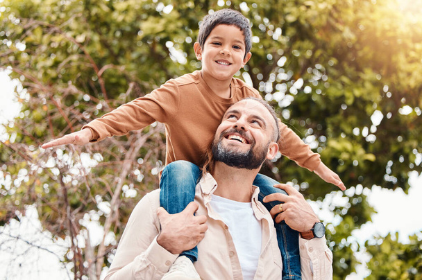Father, child and happy back ride in nature for family bonding time, summer break or holiday together outdoors. Happy dad carrying son on piggyback with smile enjoying vacation in the park outside. - Fotoğraf, Görsel