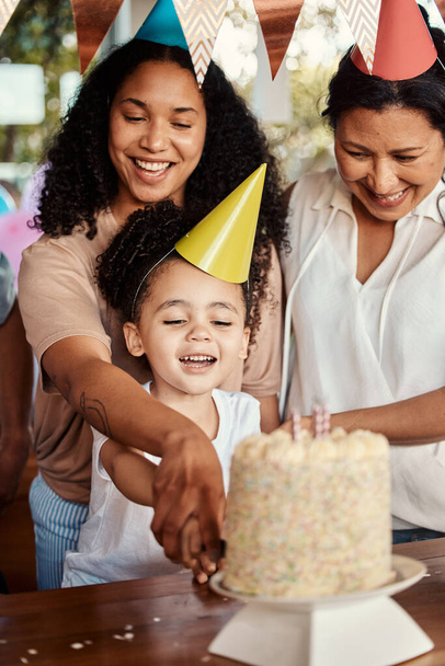 Birthday, party and cake for girl with mother and grandmother together for celebrating, bond and fun. Candle, event and child with parents and grandparent at table, happy and excited for celebration. - Foto, imagen